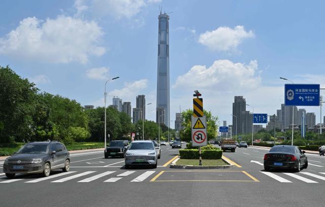 A view of the under-construction Goldin Finance 117 skyscraper is seen past traffic in Tianjin on July 14, 2026. The world's tallest unoccupied skyscraper was meant to boast a rooftop swimming pool and a luxury hotel once completed, but instead it has stood deserted in the Chinese port city of Tianjin for years. Work on the soaring Goldin Finance 117 began in 2008, but construction stalled as its developer fell into debt, and the tower remains unfinished 18 years on. (Photo by ADEK BERRY / AFP)