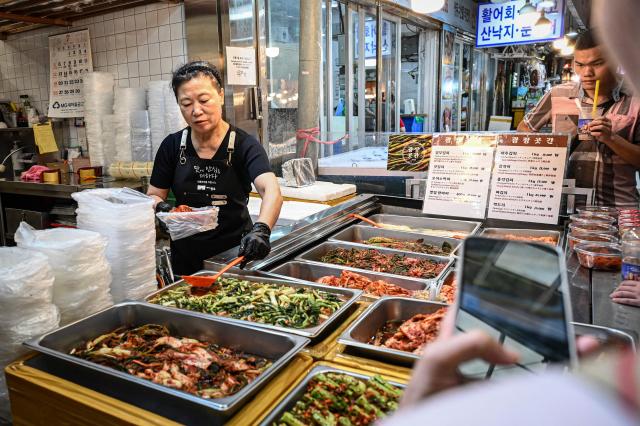 A food vendor prepares food for customers at Gwangjang Market in Seoul on July 15, 2026. (Photo by JADE GAO / AFP)