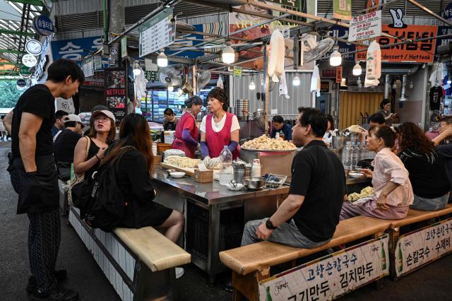 People dine at a food stall at Gwangjang Market in Seoul on July 15, 2026. (Photo by JADE GAO / AFP)