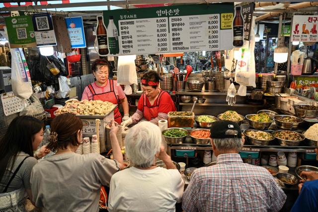 People dine at a food stall at Gwangjang Market in Seoul on July 15, 2026. (Photo by JADE GAO / AFP)