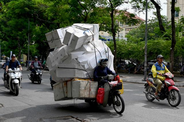 A woman rides a motorbike carrying Styrofoam boxes along a street in Hanoi on July 15, 2026. (Photo by Nhac NGUYEN / AFP)