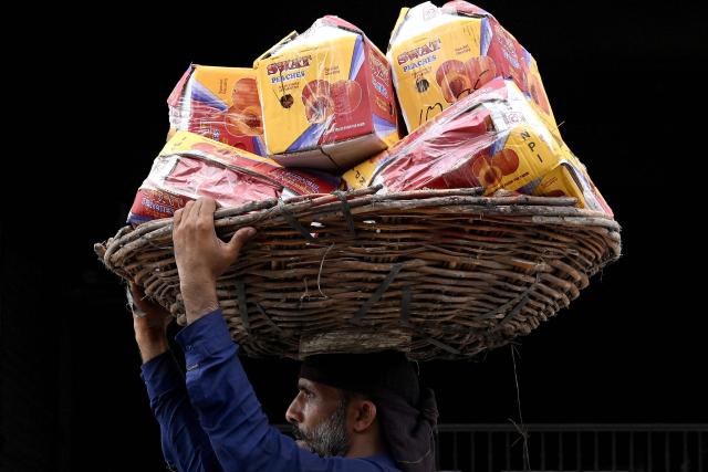 A labourer carries fruit baskets at a wholesale market in Lahore on July 15, 2026 (Photo by Arif ALI / AFP)