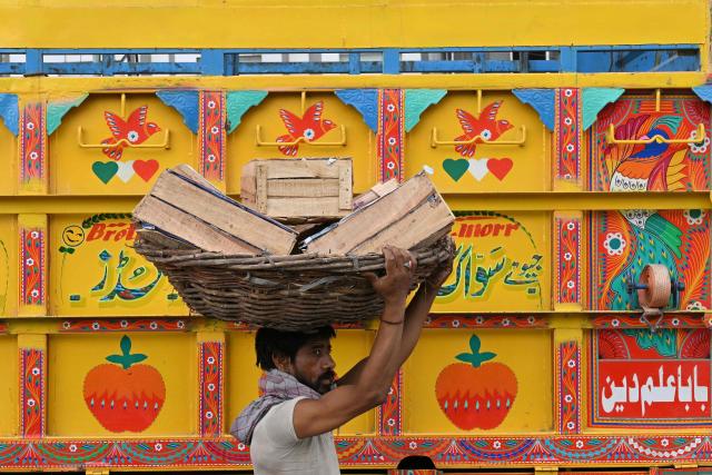 A labourer carries fruit baskets at a wholesale market in Lahore on July 15, 2026 (Photo by Arif ALI / AFP)