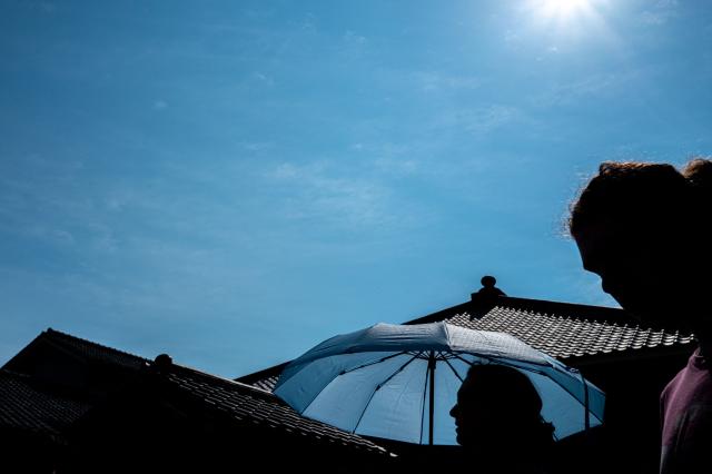 A tourist holds an umbrella to shelter from the sun while walking at the Sensoji Temple on a hot day in Tokyo on July 15, 2026. (Photo by Philip FONG / AFP)