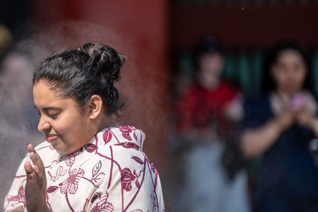 A tourist reacts next to the mist from cooling sprayers at the Sensoji Temple on a hot day in Tokyo on July 15, 2026. (Photo by Philip FONG / AFP)