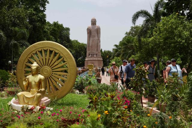 Tourists walk past a Buddha statue at the Wat Thai Temple in Sarnath, on the outskirts of Varanasi on July 15, 2026. (Photo by Niharika KULKARNI / AFP)