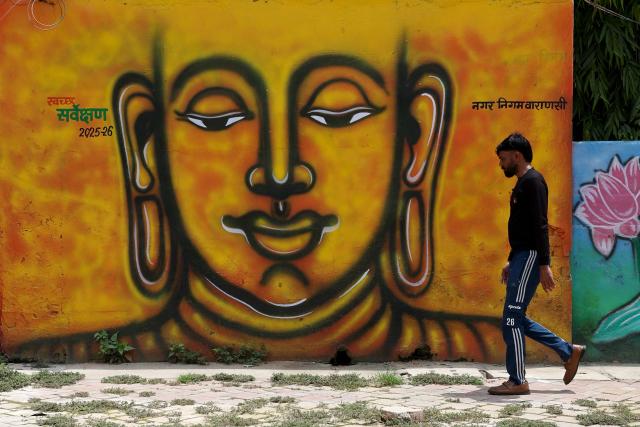 A man walks past Buddha's mural along a street in Sarnath, on the outskirts of Varanasi on July 15, 2026. (Photo by Niharika KULKARNI / AFP)