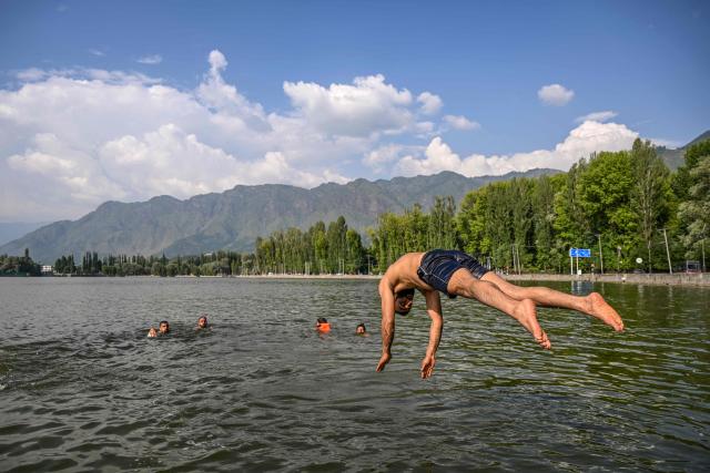 A man plunges into the waters of Dal Lake on a hot summer day in Srinagar on July 15, 2026. (Photo by Tauseef MUSTAFA / AFP)