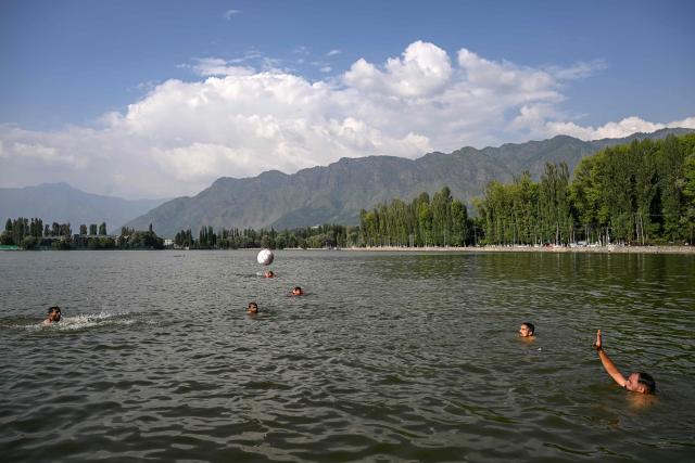 Men play with a ball in the waters of Dal Lake on a hot summer day in Srinagar on July 15, 2026. (Photo by Tauseef MUSTAFA / AFP)