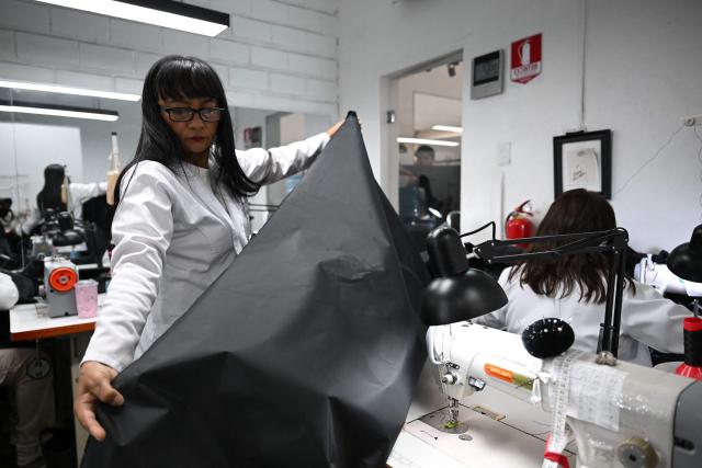 A seamstress works in the manufacture of body bags for the earthquake victims, at the ByEfrainMogollon workshop in Maracay, state of Aragua, Venezuela, on July 13, 2026. At a fashion workshop in Venezuela, the sewing machines set aside the brightly coloured threads used to make elegant dresses to sew body bags, which the creative director decided to donate to rescue workers, volunteers and relatives recovering bodies from the buildings that collapsed following the twin earthquakes measuring 7.2 and 7.5. (Photo by Raul ARBOLEDA / AFP)