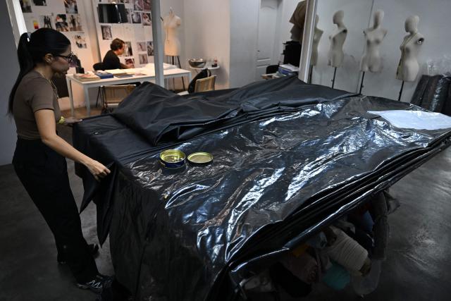 A seamstress works in the manufacture of body bags for the earthquake victims, at the ByEfrainMogollon workshop in Maracay, state of Aragua, Venezuela, on July 13, 2026. At a fashion workshop in Venezuela, the sewing machines set aside the brightly coloured threads used to make elegant dresses to sew body bags, which the creative director decided to donate to rescue workers, volunteers and relatives recovering bodies from the buildings that collapsed following the twin earthquakes measuring 7.2 and 7.5. (Photo by Raul ARBOLEDA / AFP)