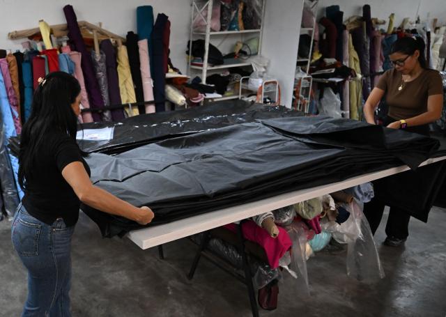 Seamstresses work in the manufacture of body bags for the earthquake victims, at the ByEfrainMogollon workshop in Maracay, state of Aragua, Venezuela, on July 13, 2026. At a fashion workshop in Venezuela, the sewing machines set aside the brightly coloured threads used to make elegant dresses to sew body bags, which the creative director decided to donate to rescue workers, volunteers and relatives recovering bodies from the buildings that collapsed following the twin earthquakes measuring 7.2 and 7.5. (Photo by Raul ARBOLEDA / AFP)