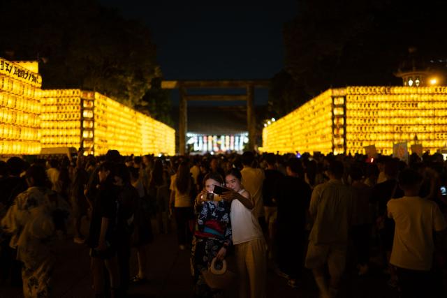 People gather in front of thousands of lanterns on display during the Mitama Matsuri, one of the capital's largest summer "obon" festivals, at Yasukuni Shrine in Tokyo on July 15, 2026. (Photo by Philip FONG / AFP)