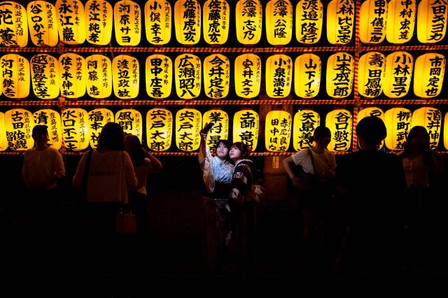 People gather in front of thousands of lanterns on display during the Mitama Matsuri, one of the capital's largest summer "obon" festivals, at Yasukuni Shrine in Tokyo on July 15, 2026. (Photo by Philip FONG / AFP)