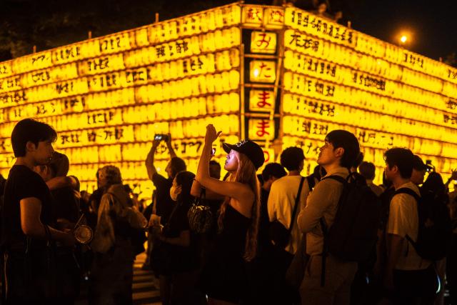 People gather in front of thousands of lanterns on display during the Mitama Matsuri, one of the capital's largest summer "obon" festivals, at Yasukuni Shrine in Tokyo on July 15, 2026. (Photo by Philip FONG / AFP)