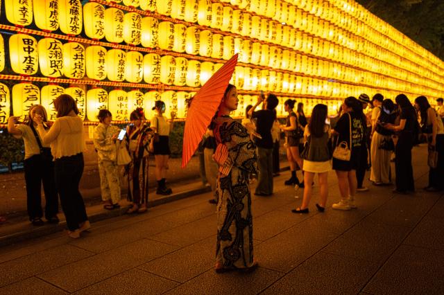 People gather in front of thousands of lanterns on display during the Mitama Matsuri, one of the capital's largest summer "obon" festivals, at Yasukuni Shrine in Tokyo on July 15, 2026. (Photo by Philip FONG / AFP)