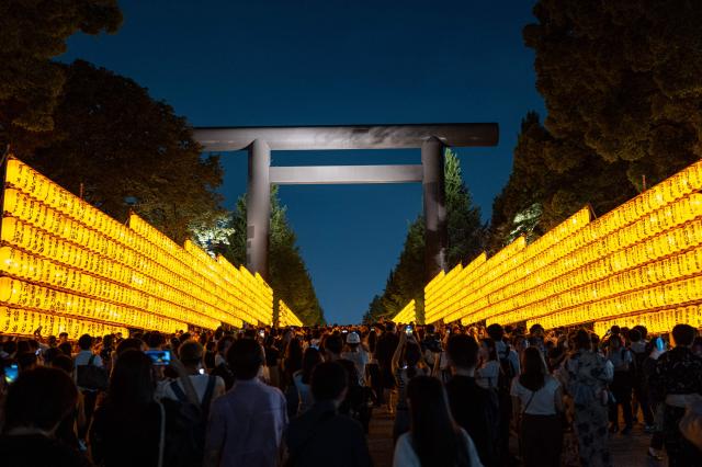 People gather in front of thousands of lanterns on display during the Mitama Matsuri, one of the capital's largest summer "obon" festivals, at Yasukuni Shrine in Tokyo on July 15, 2026. (Photo by Philip FONG / AFP)
