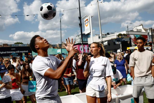 A competitor (L) shows off his football skills as he takes part in an England football player Jude Bellingham lookalike competition, outside the Boxpark Shoreditch event space in London on July 15, 2026, just hours before fans watch a live broadcast of the 2026 World Cup semifinal between England and Argentina. (Photo by Brook Mitchell / AFP)