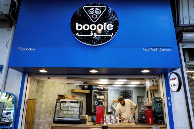 A barista prepares a drink at a coffee shop along a street in central Tehran on July 15, 2026. Hostilities renewed between Iran and the US, endangering a memorandum of understanding, reached in June with Qatari and Pakistani mediation, aimed at ending the war. The confrontation resumed on July 7 after attacks on ships in the Gulf, which Iran has attributed to Iran. (Photo by AFP) / 