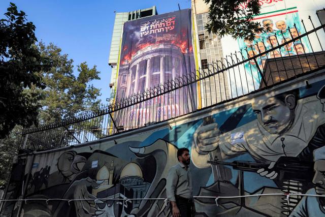 A huge anti-US billboard featuring a burning White House with the US President and his family members in coffins, alongside text in Persian reading "blood for blood" is displayed on the facade of a building in Tehran's Palestine Square on July 15, 2026. Hostilities renewed between Iran and the US, endangering a memorandum of understanding, reached in June with Qatari and Pakistani mediation, aimed at ending the war. The confrontation resumed on July 7 after attacks on ships in the Gulf, which Iran has attributed to Iran. (Photo by AFP) / 
