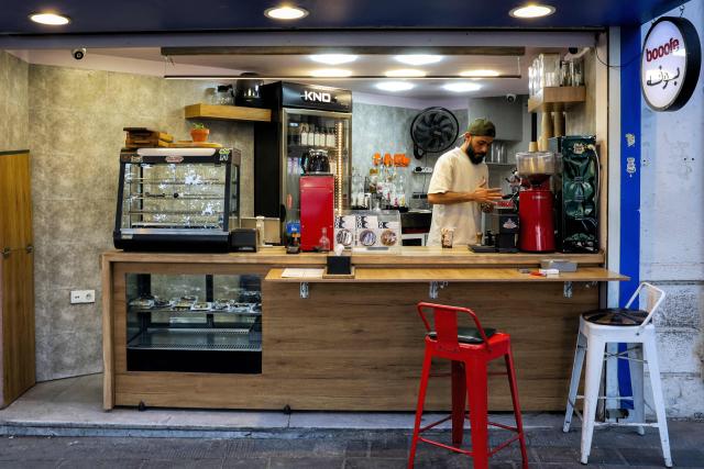 A barista prepares a drink at a coffee shop along a street in central Tehran on July 15, 2026. Hostilities renewed between Iran and the US, endangering a memorandum of understanding, reached in June with Qatari and Pakistani mediation, aimed at ending the war. The confrontation resumed on July 7 after attacks on ships in the Gulf, which Iran has attributed to Iran. (Photo by AFP) / 