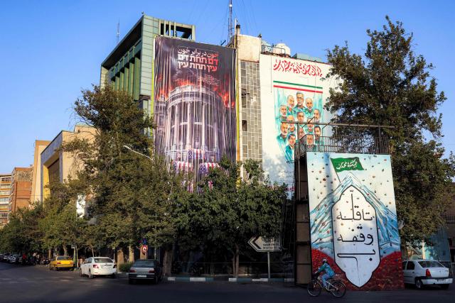 A huge anti-US billboard featuring a burning White House with the US President and his family members in coffins, alongside text in Persian reading "blood for blood" is displayed on the facade of a building in Tehran's Palestine Square on July 15, 2026. Hostilities renewed between Iran and the US, endangering a memorandum of understanding, reached in June with Qatari and Pakistani mediation, aimed at ending the war. The confrontation resumed on July 7 after attacks on ships in the Gulf, which Iran has attributed to Iran. (Photo by AFP) / 