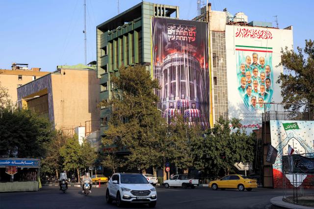 A huge anti-US billboard featuring a burning White House with the US President and his family members in coffins, alongside text in Persian reading "blood for blood" is displayed on the facade of a building in Tehran's Palestine Square on July 15, 2026. Hostilities renewed between Iran and the US, endangering a memorandum of understanding, reached in June with Qatari and Pakistani mediation, aimed at ending the war. The confrontation resumed on July 7 after attacks on ships in the Gulf, which Iran has attributed to Iran. (Photo by AFP) / 