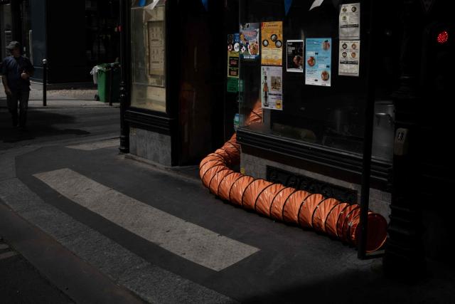 This photograph shows an air conditioning exhaust pipe emerging from a restaurant's doorway in Paris on July 15, 2026. (Photo by JOEL SAGET / AFP)