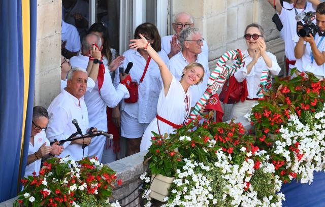 French TV host Maya Lauque (C) waves to the crowd from the Town Hall balcony before taking part in the traditional throwing of the symbolic "keys to the city" during the opening ceremony of the "Fetes de Bayonne" (Bayonne Festival) in Bayonne, south-western France on July 15, 2026. The Bayonne Festival runs from July 15 to July 19, 2026. (Photo by Gaizka IROZ / AFP)