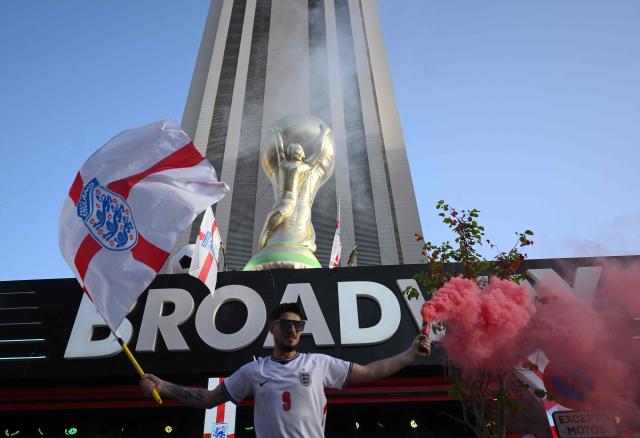 An England's supporter cheers in front of the Broadway club, underneath an inflatable WC trophy, in Benidorm, on Spain's eastern coast, on July 15, 2026 prior the 2026 World Cup semi-final match between England and Argentina on a giant screen. (Photo by JOSE JORDAN / AFP)
