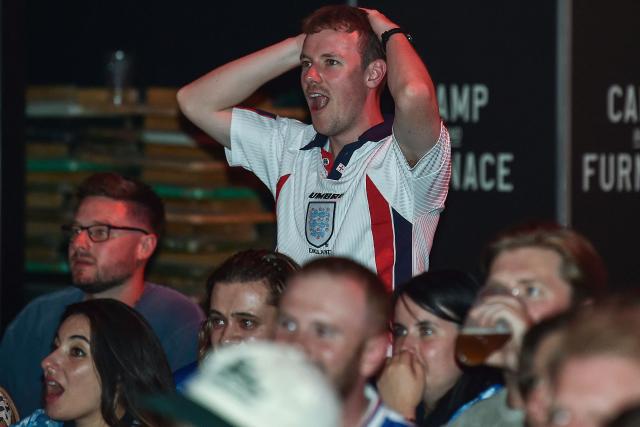 England supporters react as they watch a live broadcast of the 2026 World Cup semifinal football match between England and Argentina, at the Camp and Furnace in Liverpool, north-west England, on July 15, 2026. (Photo by PETER POWELL / AFP)