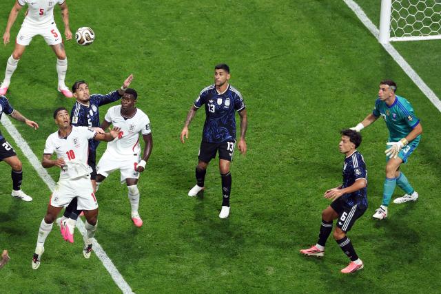 Argentina's midfielder #05 Leandro Paredes jumps to head the ball next to England's midfielder #10 Jude Bellingham and England's defender #06 Marc Guehi as Argentina's goalkeeper #23 Emiliano Martinez (R) looks on during the 2026 World Cup football tournament semi-final match between England and Argentina at the Atlanta Stadium in Atlanta on July 15, 2026.  (Photo by PATRICIA DE MELO MOREIRA / AFP)