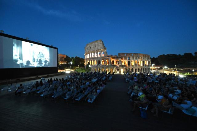 Attendees watch a film during the summer edition of Cinema Festival "QUO VADIS?", at Temple of Venus, the ancient Roman Forum with the ancient Colosseum in the background, in Rome on July 15, 2026. (Photo by Andreas SOLARO / AFP)