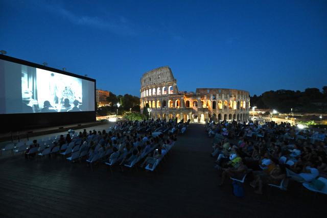 Attendees watch a film during the summer edition of Cinema Festival "QUO VADIS?", at Temple of Venus, the ancient Roman Forum with the ancient Colosseum in the background, in Rome on July 15, 2026. (Photo by Andreas SOLARO / AFP)