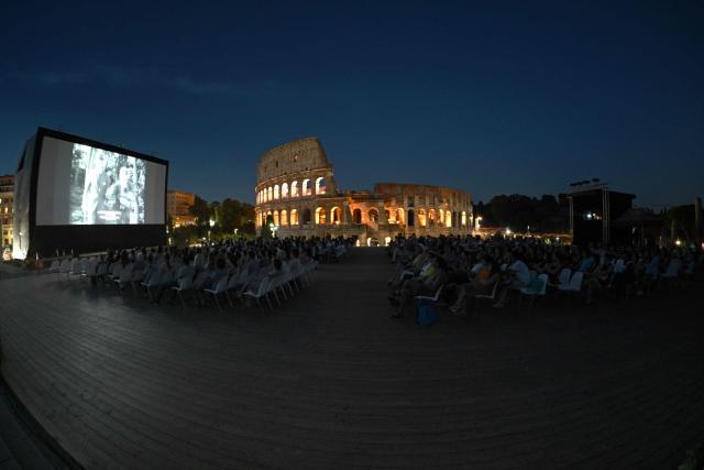Attendees watch a film during the summer edition of Cinema Festival "QUO VADIS?", at Temple of Venus, the ancient Roman Forum with the ancient Colosseum in the background, in Rome on July 15, 2026. (Photo by Andreas SOLARO / AFP)
