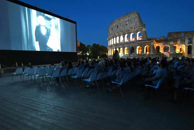 Attendees watch a film during the summer edition of Cinema Festival "QUO VADIS?", at Temple of Venus, the ancient Roman Forum with the ancient Colosseum in the background, in Rome on July 15, 2026. (Photo by Andreas SOLARO / AFP)