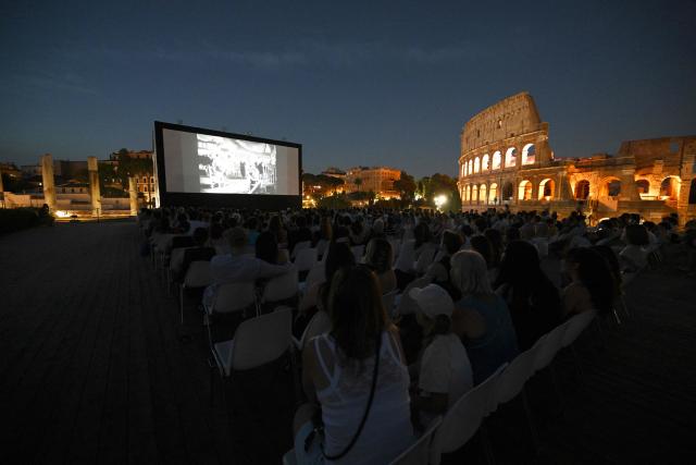 Attendees watch a film during the summer edition of Cinema Festival "QUO VADIS?", at Temple of Venus, the ancient Roman Forum with the ancient Colosseum in the background, in Rome on July 15, 2026. (Photo by Andreas SOLARO / AFP)