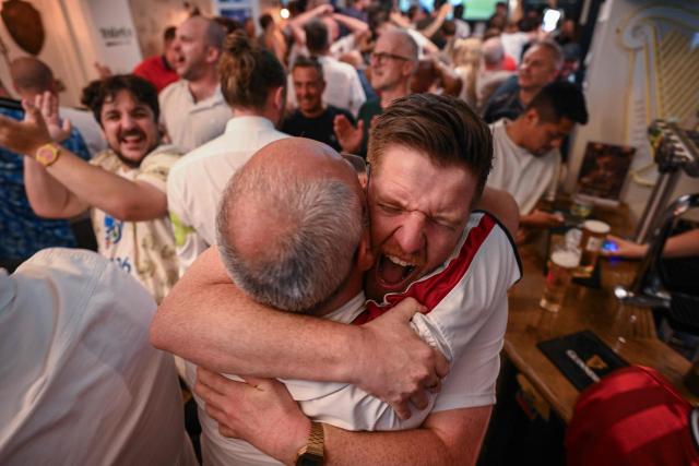 England supporters cheer after the team's first goal as they watch a live broadcast of the 2026 World Cup semifinal football match between England and Argentina, at Tailors pub in the town of Cheltenham, western England, on July 15, 2026. (Photo by Oli SCARFF / AFP)