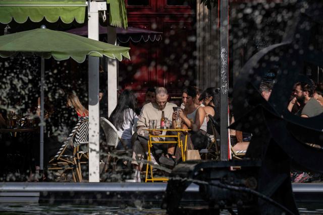 Clients enjoy beverages at the terrace of a cafe in central Paris on July 15, 2026. The Paris region, and large parts of the rest of France, is currently experiencing the third heatwave since May 2026, increasing the risk of fires. The three heatwaves have seen temperature records broken in several countries across Europe and have caused thousands of excess deaths, according to estimates in Belgium, Britain, France and Spain. (Photo by Martin LELIEVRE / AFP)