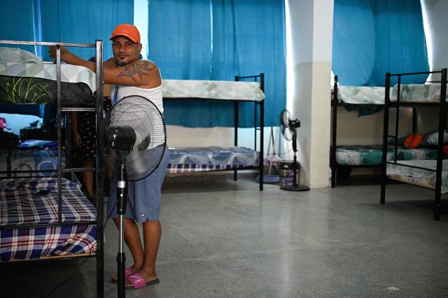 An earthquake-displaced resident who lived in La Guaira stands next to bunk beds inside a temporary shelter at the Jose Gervasio Artigas Educational Complex in Propatria, Caracas, on July 15, 2026, following the June 24 twin earthquakes. The death toll from the earthquakes that struck Venezuela almost three weeks ago has surpassed 4,700, while almost 17,000 people have been injured, an official report released on July 14, 2026 stated. (Photo by Federico PARRA / AFP)