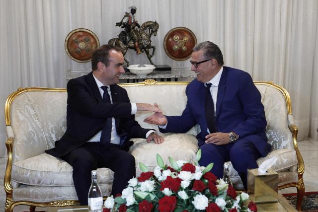 French Prime Minister Sébastien Lecornu (L) shakes hands with Moroccan Prime Minister Aziz Akhannouch upon his arrival at Rabat-Salé Airport in Rabat on July 15, 2026. (Photo by Abdel Majid BZIOUAT / AFP)
