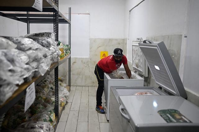 A school staff member organizes food inside a freezer at a temporary shelter camp for people displaced from La Guaira at the Jose Gervasio Artigas Educational Complex in Propatria, Caracas, on July 15, 2026, following the June 24 twin earthquakes. The death toll from the earthquakes that struck Venezuela almost three weeks ago has surpassed 4,700, while almost 17,000 people have been injured, an official report released on July 14, 2026 stated. (Photo by Federico PARRA / AFP)