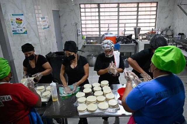 School staff prepare arepas for people displaced from La Guaira inside a temporary shelter camp at the Jose Gervasio Artigas Educational Complex in Propatria, Caracas, on July 15, 2026, following the June 24 twin earthquakes. The death toll from the earthquakes that struck Venezuela almost three weeks ago has surpassed 4,700, while almost 17,000 people have been injured, an official report released on July 14, 2026 stated. (Photo by Federico PARRA / AFP)