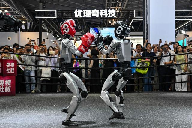 Humanoid robots controlled by a remote control by Unitree Robotics take part in a fight during the World Artificial Intelligence Conference (WAIC) in Shanghai on July 18, 2026. (Photo by Hector RETAMAL / AFP)