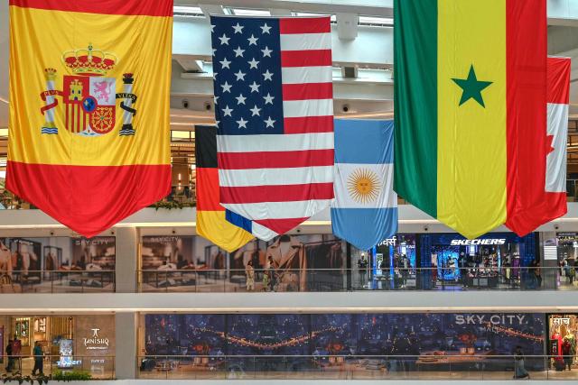 Shoppers walk past an installation featuring flags of countries participating in the 2026 FIFA World Cup football tournament at the Sky City mall in Mumbai on July 18, 2026 on the eve of the World Cup football final match between Spain and Argentina. (Photo by Indranil MUKHERJEE / AFP)
