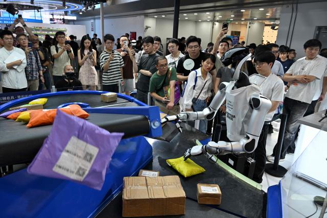 A humanoid robot by Robotera is seen working with packages during the World Artificial Intelligence Conference (WAIC) in Shanghai on July 18, 2026. (Photo by Hector RETAMAL / AFP)