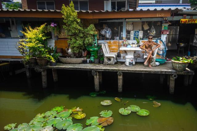 A man wears sunglasses as he sits in front of a residence along a canal in Bangkok on July 18, 2026. (Photo by Candida NG / AFP)