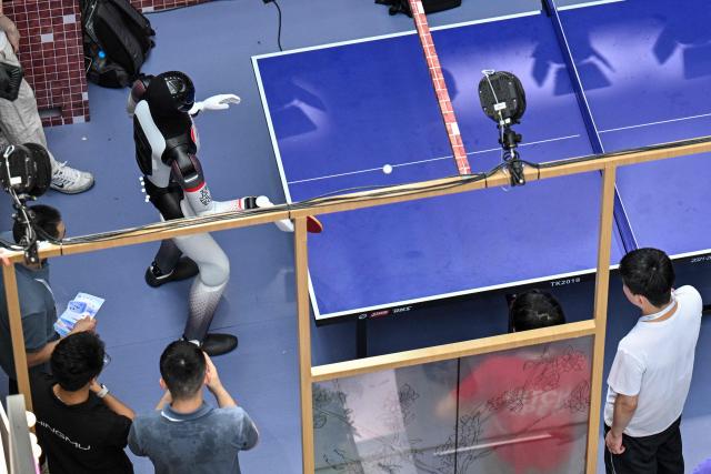 A humanoid robot plays ping pong during the World Artificial Intelligence Conference (WAIC) in Shanghai on July 18, 2026. (Photo by Hector RETAMAL / AFP)