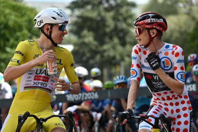 UAE Team Emirates - XRG's Slovenian rider Tadej Pogacar wearing the overall leader's yellow jersey (L) speaks with Team Visma | Lease a Bike's Danish rider Jonas Vingegaard wearing the climber's dotted "King of the Mountains" jersey at the start of the 14th stage of the 113th edition of the Tour de France cycling race, 155,3 km between Mulhouse and Le Markstein in the Vosges mountains, on July 18, 2026. (Photo by Jeff PACHOUD / AFP)