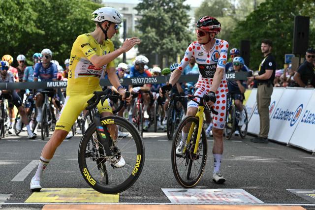 UAE Team Emirates - XRG's Slovenian rider Tadej Pogacar wearing the overall leader's yellow jersey (L) speaks with Team Visma | Lease a Bike's Danish rider Jonas Vingegaard wearing the climber's dotted "King of the Mountains" jersey at the start of the 14th stage of the 113th edition of the Tour de France cycling race, 155,3 km between Mulhouse and Le Markstein in the Vosges mountains, on July 18, 2026. (Photo by Jeff PACHOUD / AFP)
